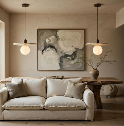 Paire de suspensions marbre et verre opalin au-dessus d'un canapé lin beige, décoration Wabi-Sabi