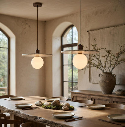 Trois suspensions marbre opalin au-dessus d'une table en bois dans une salle à manger, déco artisanale Wabi-Sabi