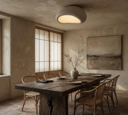 Plafonnier galet Wabi-Sabi au-dessus d'une table en bois brut, salle à manger esprit slow design